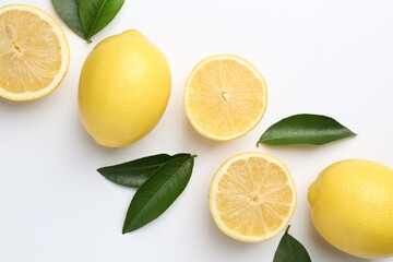 Fresh yellow lemons and green leaves on white background, flat lay