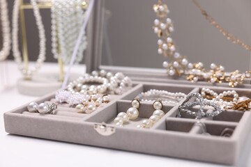 Different stylish jewellery in box on white table, closeup