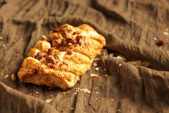 Pecan braid. A puff pastry roll, often Danish-style, filled with a creamy mixture of pecans and sugar. Black background.