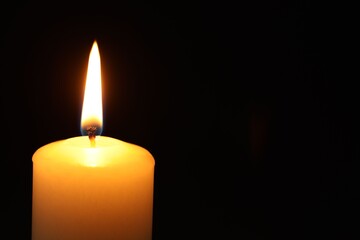 One burning candle on black background, closeup. Space for text