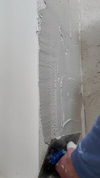 Worker uses a trowel to spread plaster smoothly on the wall surfaces during renovations. The process shows steps needed for proper wall finishing.