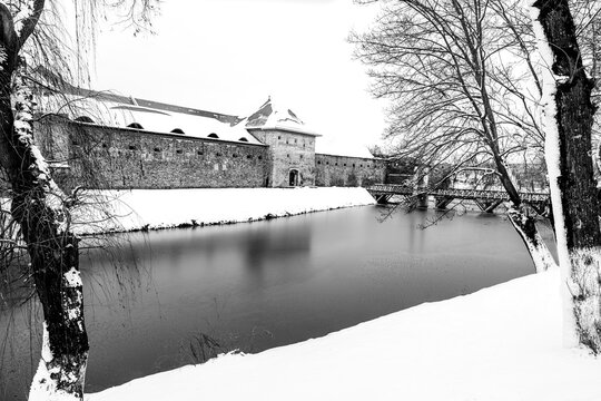 Fagaras, Transylvania, Brasov county, Romania: Fagaras Citadel covered in show; medieval fortress on the shores of the frozen lake in black and white