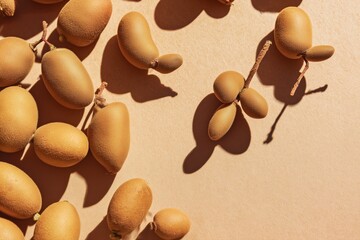 Golden tamarind fruits scattered artistically on a warm surface, showcasing their unique shapes and shadows in gentle afternoon light