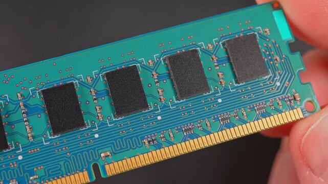 DDR RAM memory chips module macro view. Hand holding Random Access Memory RAM module disconnected from computer motherboard. Manufacturers redirect capacity production for AI data centers processing.
