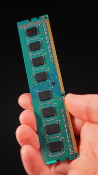 DDR RAM memory chips module. Hand holding Random Access Memory RAM module disconnected from computer motherboard. Manufacturers redirect capacity production for AI data centers. Vertical.
