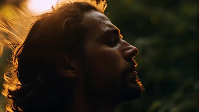 Man enjoys sunlight in forest during golden hour, breathing deeply and feeling nature around him in a quiet moment of reflection