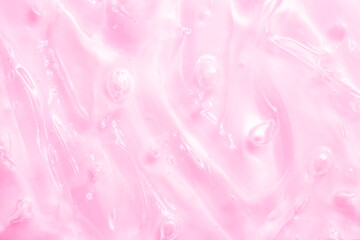 Fototapeta premium Cosmetic gel, serum, clear sample with a pink tint, close-up. Liquid cream with a foaming texture. Gel-like texture of a cosmetic product. Liquid cosmetic lotion for skin care.