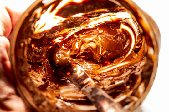 Closeup of the inside of a nearly empty jar of hazelnut spread with a silver butter knife inside