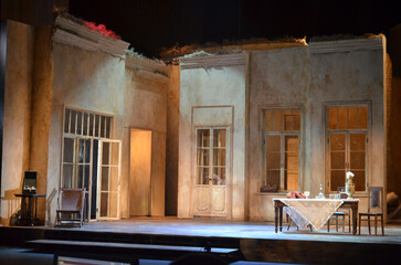 Theater stage set with vintage interior design, realistic house facade scenery, dramatic lighting, empty performance scene prepared for play or rehearsal. © Ilya K.