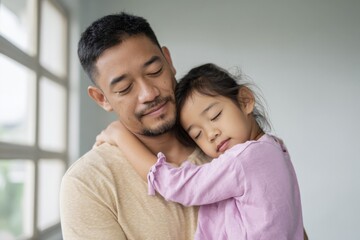 Fototapeta premium Asian father and daughter embracing in warm moment by window