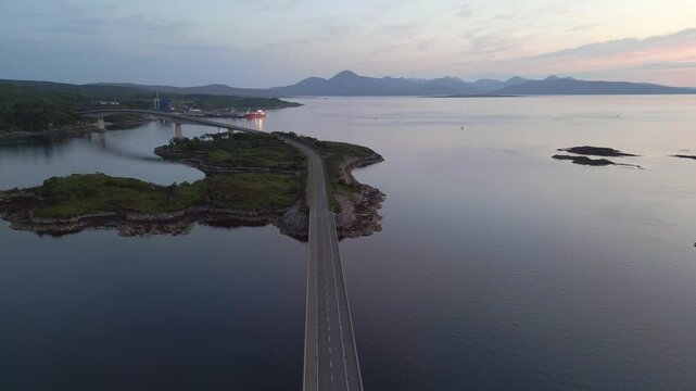 Un pont qui relit entre elle des &icirc;les , avec une chaine de montagne en fond et au coucher de soleil