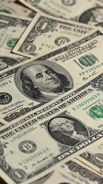 One hundred dollar bill on a flat, rotating table, surrounded by more dollars