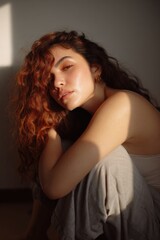 Young caucasian female with curly red hair sitting in sunlight