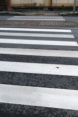 Worn white stripes on asphalt curb with tram lines and snow patches