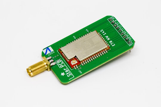 Green wireless transceiver module PCB with shielded RF module and gold SMA antenna connector isolated on white background