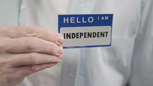 independence demonstrating with badge Blue name tag independent on shirt closeup hands affixing badge to light shirt pocket
