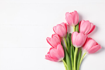 Naklejka premium Bouquet of pink tulips on white wooden table, top view. Space for text
