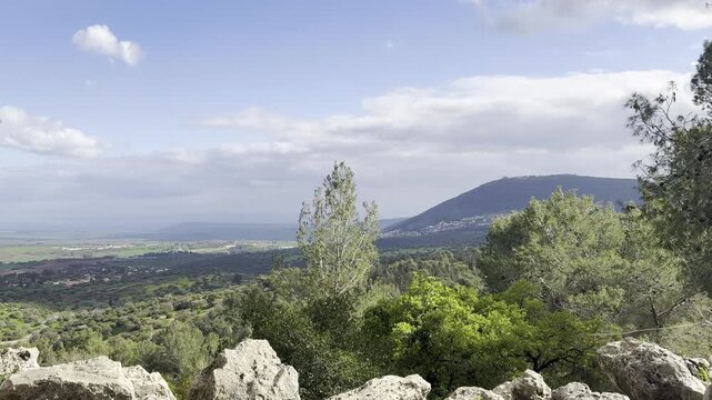 View of Mount Tabor through a ridge of stones, trees, and valley in Beit Keshet nature reserve in Israel, spring.