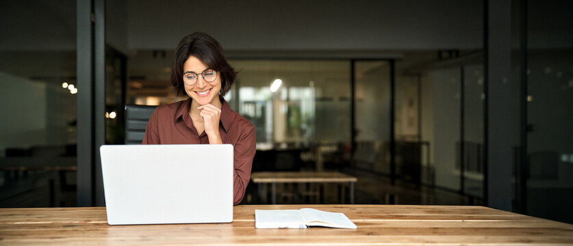 Young happy professional business woman executive working on computer technology in office, busy smiling businesswoman entrepreneur or hr manager using laptop sitting at work desk. Copy space for ads.