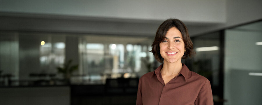 Young happy smiling Hispanic businesswoman leader, female company worker or corporate manager, confident business woman entrepreneur looking at camera at work. Headshot close up face portrait.