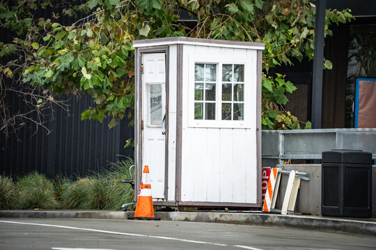Small white security guard booth with an open door and a traffic cone outside