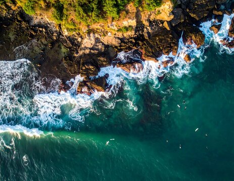 Rocky coast meets turquoise ocean, waves crashing, surfers waiting, sunlit