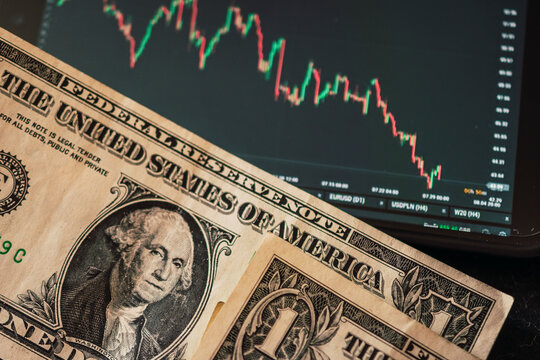 American dollar bills next to a downward-sloping chart of a stock broker

