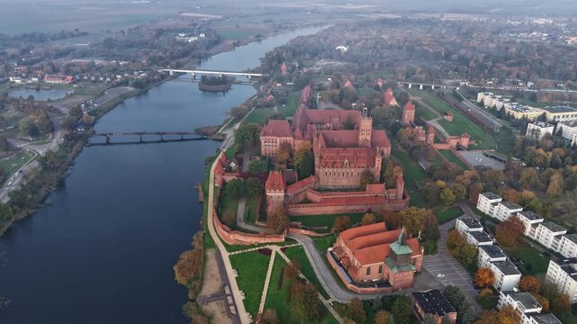Malbork Castle aerial drone time lapse over medieval brick fortress and river landscape in autumn mist
