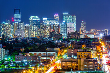 Naklejka premium Jersey City skyline rise behind Hoboken city by night.