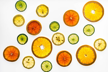 Slices of oranges, lemons and limes scattered on a bright white surface.