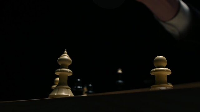 Close-up of a chess player's hands as they checkmate their opponent. Chess game on a black background, with the queen eating the king