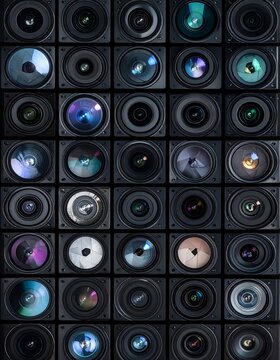 Array of camera lenses, various reflections within, black on black grid