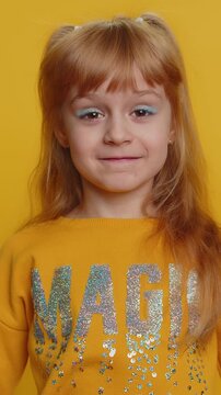 Excited amazed young preteen child girl kid looking shocked surprised wow showing hands brain explosion gesture. Little toddler children touching her head and showing explosion on yellow background