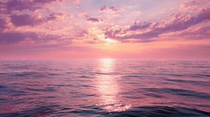 Fototapeta premium A view of the ocean at sunset shows a gentle horizon. The sky turns pink and purple while the water reflects these colors. The scene captures the end of the day.