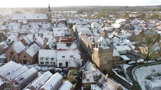 Hattem, the Netherlands - January 6th 2026: Beautiful aerial footage. Drone panning around the medieval Dijkpoort gate during a snowy winters day. 