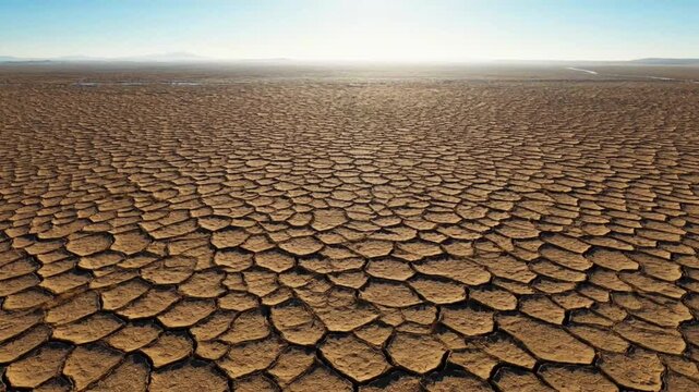 Dry cracked earth landscape with blue sky, arid terrain with parched soil