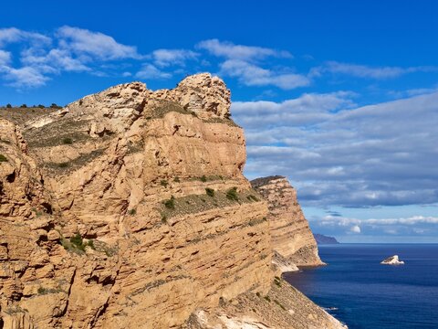 Sunny coastal cliffs with ferry and waves, Majestic sandstone cliffs overlooking calm sea with ferry nearby