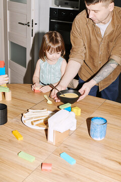 Family breakfast time with child engaging in playful activities