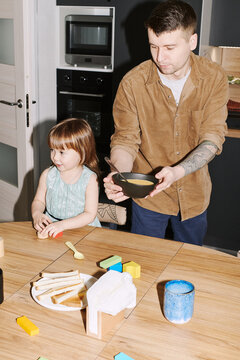 Family breakfast time with child engaging in playful activities