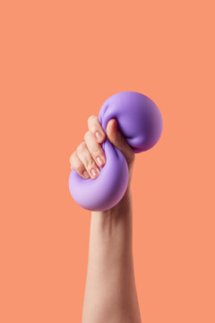 Woman hand dividing squish into two halves over orange background