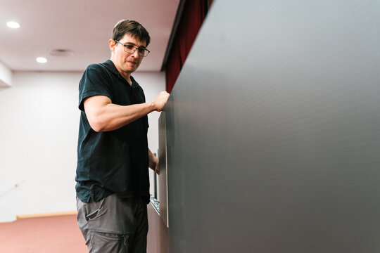 Man technician fixing LED display in auditorium