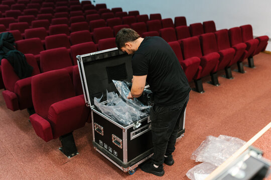 Adult man unpacking LED display inbox while working in auditorium