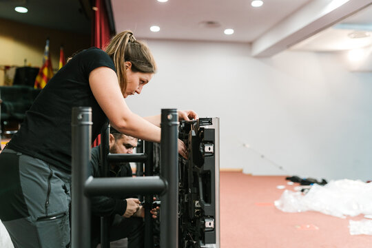 Concentrated female technician fixing LED display in auditorium