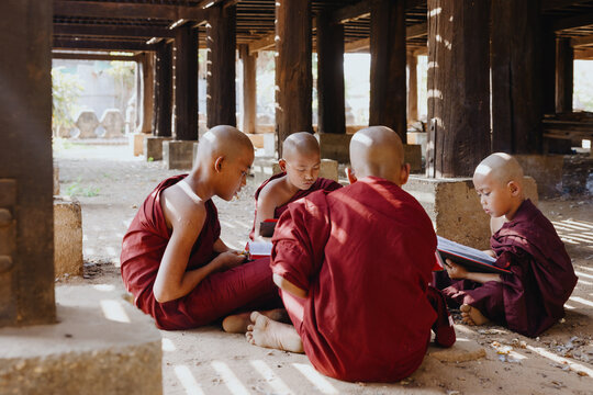 Young Monks studying scriptures under wooden pillars