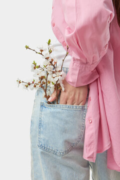 Back of woman placing hand into pocket of trousers with spring bouquet