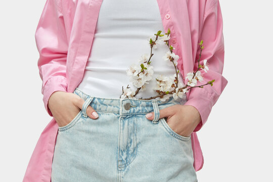 Carefree person standing with hands on hips and branch of apricot tree