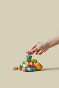 Close up of female hand putting polyhedron wooden block on top of heap