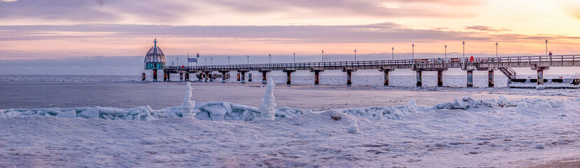 Zinnowitz – Seebrücke an der zugefrorenen Ostsee auf Usedom, Eisskulpturen am Strand bei Sonnenaufgang im Winter, seltenes Naturschauspiel © stylefoto24