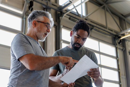 Coworkers discussing over document in automobile industry