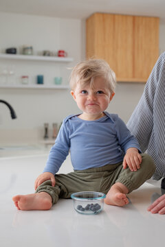 Portrait of todder sitting on kitchen counter.